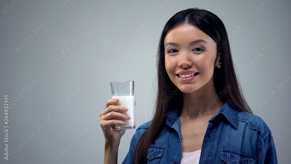 Smiling woman holding glass of fresh milk, lactose-free dairy products, calcium Smiling woman holding glass of fresh milk, lactose-free dairy products, calcium