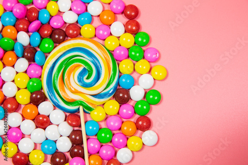 Colorful lollipop and different colored round candy. Top view pink pastel background