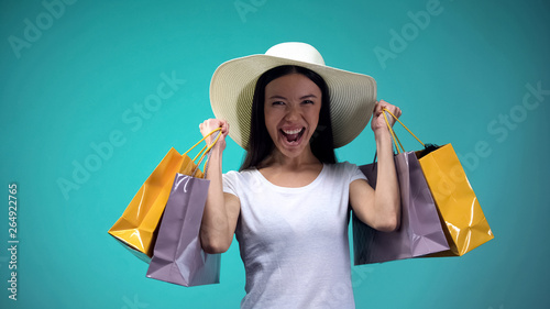 Cheerful asian girl in panama holding many paper bags, shopping, womens hobby