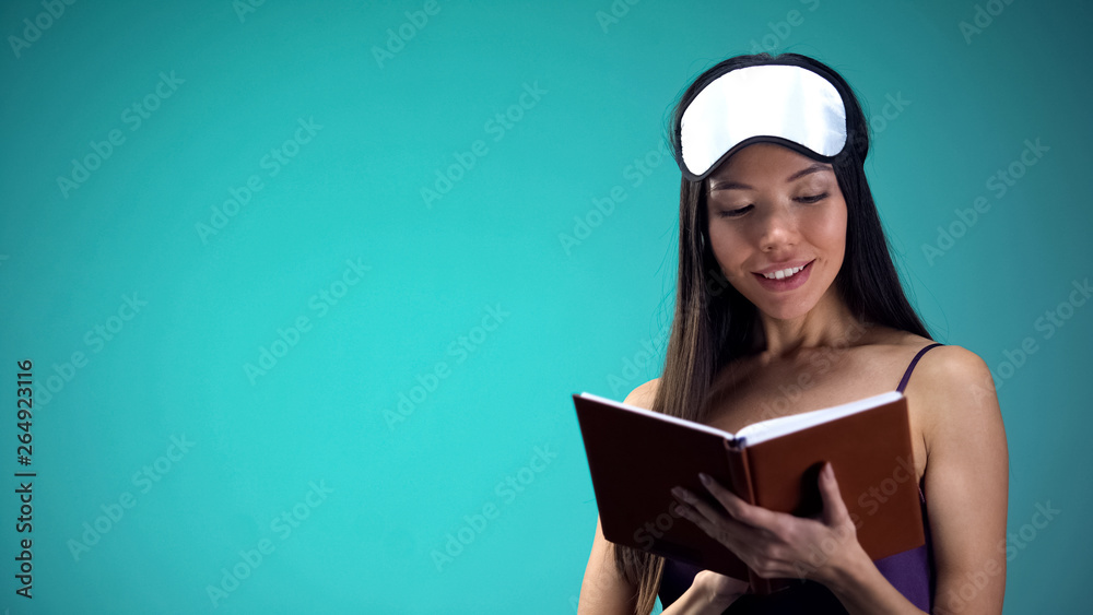 Pretty female in pajamas reading book before sleeping, relaxing bedtime ritual Pretty female in pajamas reading book before sleeping, relaxing bedtime ritual