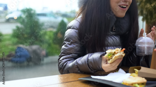 Happy female holding sandwich having dinner cafe  homeless person lying outdoor