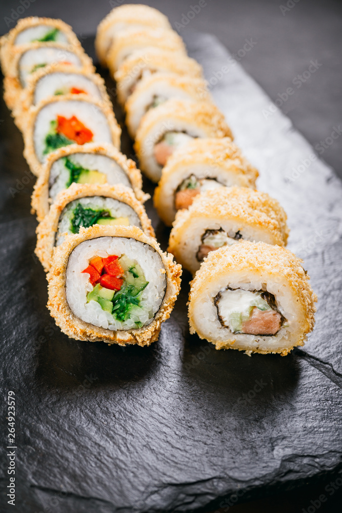 sushi, japanese food, deluxe restaurant menu, delicious traditional seafood. philadelphia and vegetarian tempura sushi rolls, served on black plate sushi, japanese food, deluxe restaurant menu, delicious traditional seafood. philadelphia and vegetarian tempura sushi rolls, served on black plate