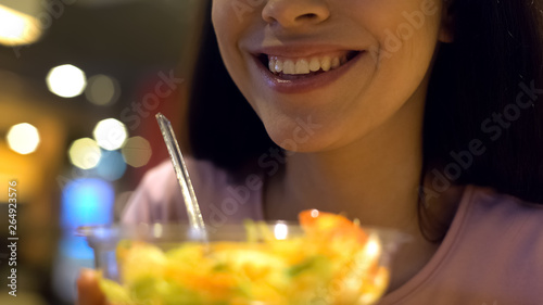 Obraz na plátně Smiling woman holding vegetable salad closeup sitting in cafe, healthy lifestyle
