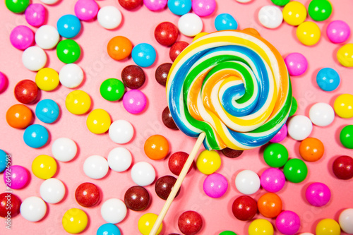 Colorful lollipop and different colored round candy. Top view pink pastel background
