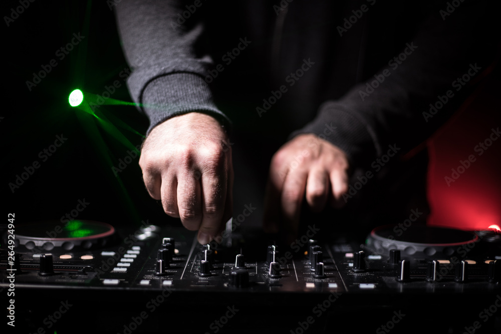 DJ Spinning, Mixing, and Scratching in a Night Club, Hands of dj tweak various track controls on dj's deck, strobe lights and fog, or Dj mixes the track in the nightclub at party. DJ Spinning, Mixing, and Scratching in a Night Club, Hands of dj tweak various track controls on dj's deck, strobe lights and fog, or Dj mixes the track in the nightclub at party.