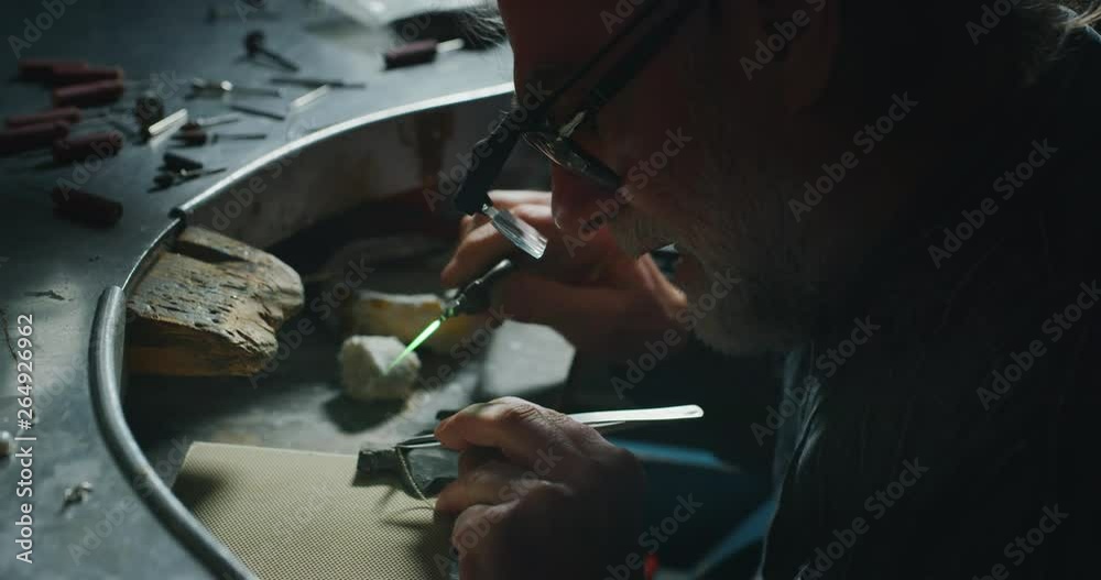 Slow motion of experienced goldsmith working on a handmade jewelry bracelet chain of precious metal white gold in a workshop.Shot in 8K.Concept of jewelry, luxury,goldsmith,gold,silver,precious metals