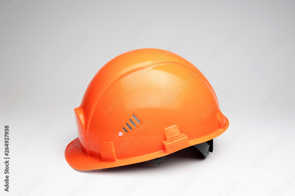 Orange construction helmet on a light background. The concept of architecture, construction, engineering, design. Copy space. Orange construction helmet on a light background. The concept of architecture, construction, engineering, design. Copy space.