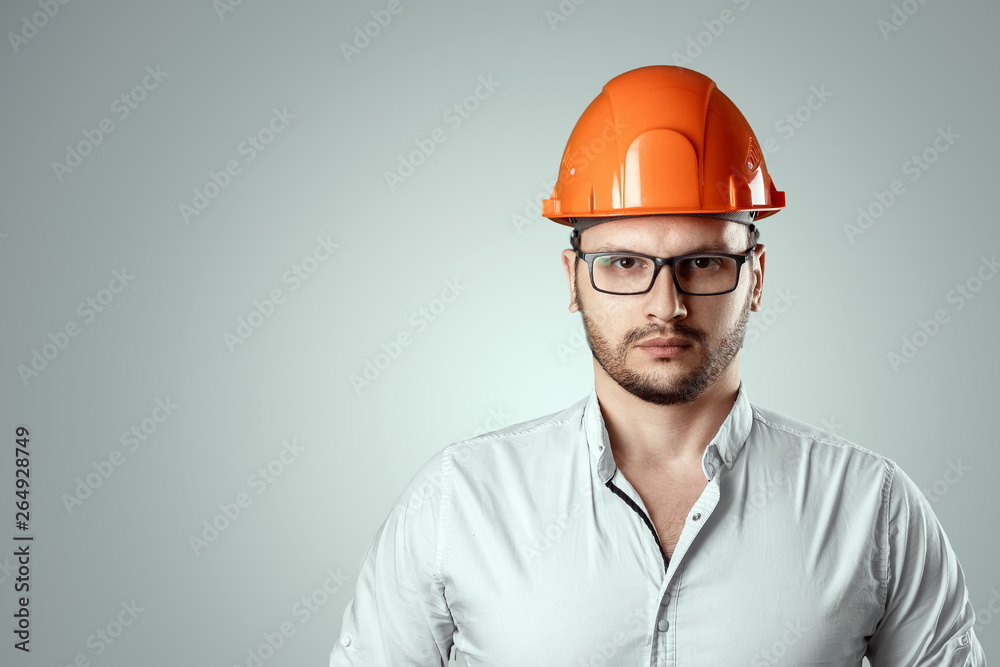 Portrait of a man in a construction orange helmet on a light background. Concept architecture, construction, engineering, design, repair. Copy space Portrait of a man in a construction orange helmet on a light background. Concept architecture, construction, engineering, design, repair. Copy space