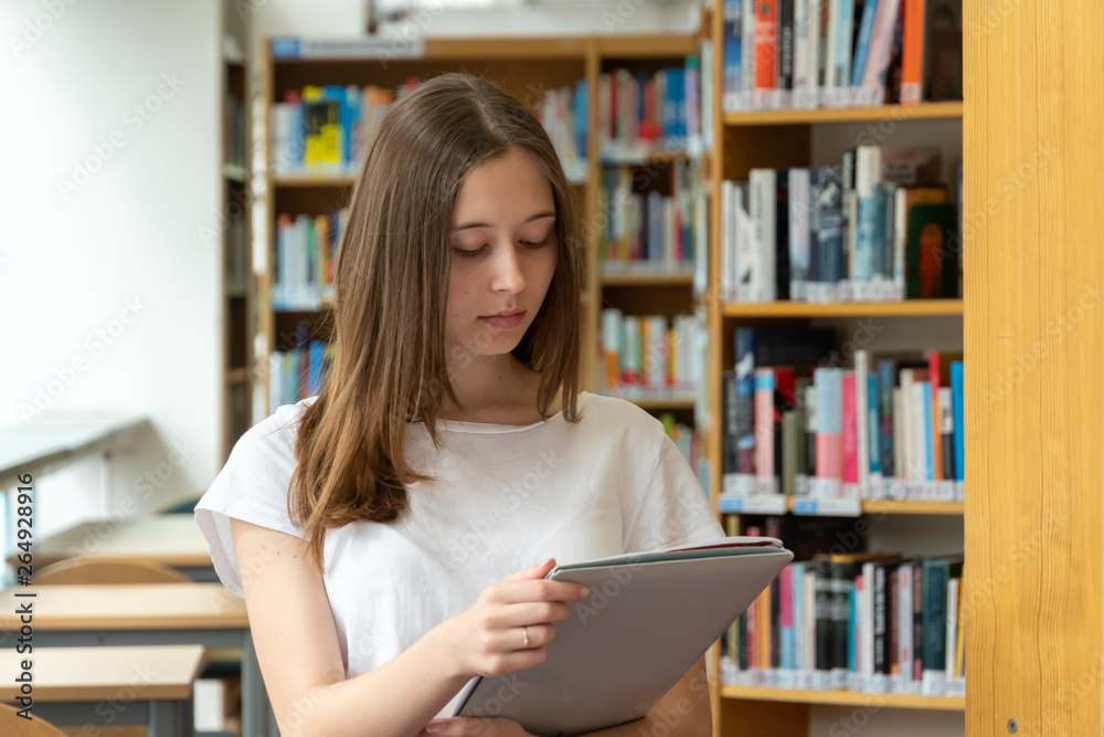 Portrait of a concentrated girl standing reading in the school library Portrait of a concentrated girl standing reading in the school library