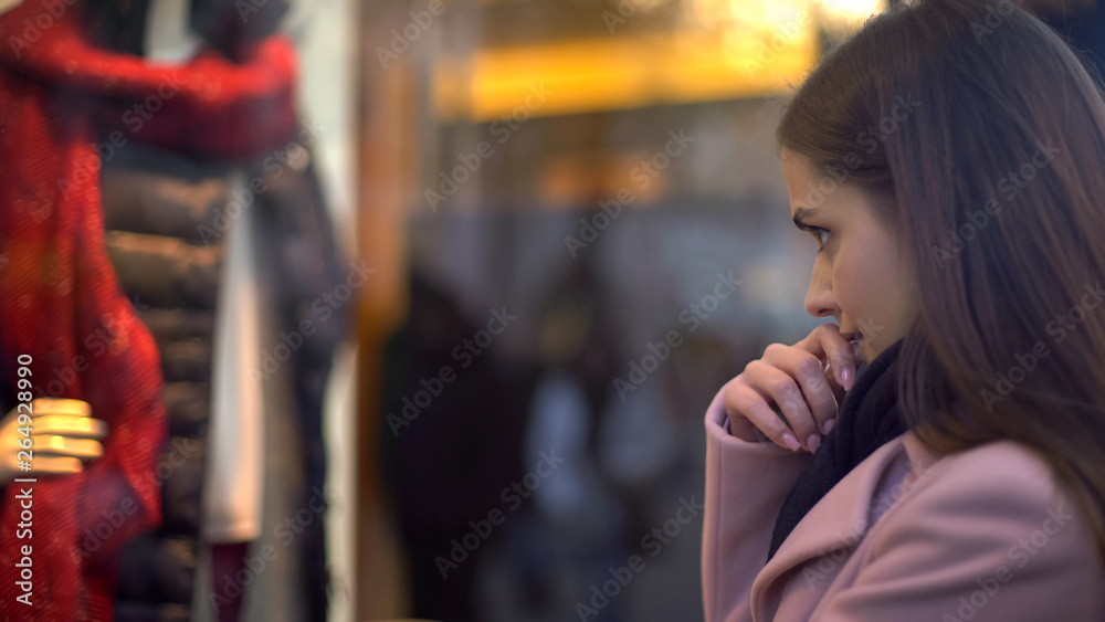 Beautiful lady looking at clothing in shop window, having not enough money Beautiful lady looking at clothing in shop window, having not enough money