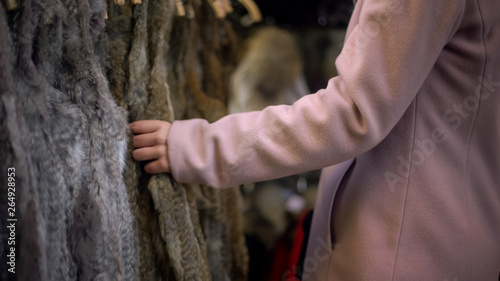 Young female looking at fur coats at street market, shopping and consumerism
