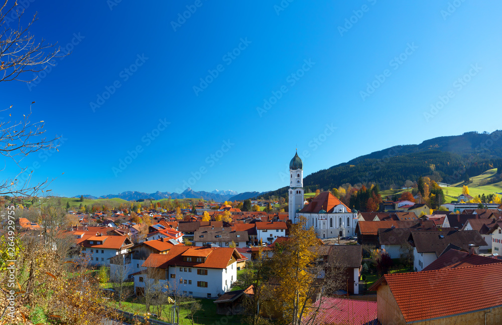 Blue sky in autumn over Nesselwang in Allgäu, Bavaria, Germany, with the alps in the background.