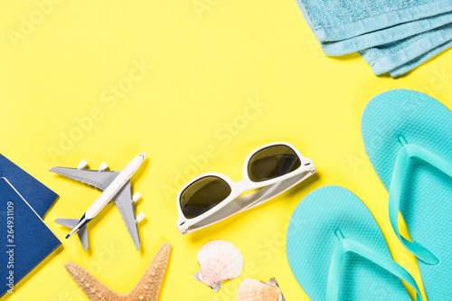 Blue flip flops, sunglasses, passport and starfish on yellow background. © nadianb