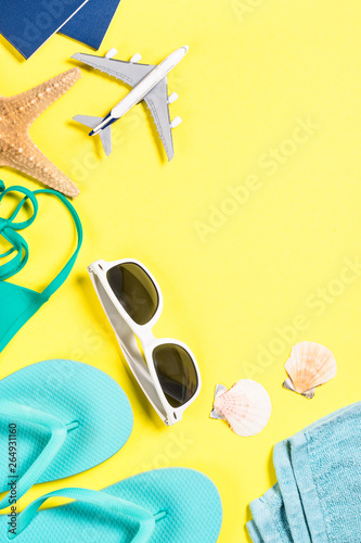 Blue flip flops, sunglasses, passport and starfish on yellow background.