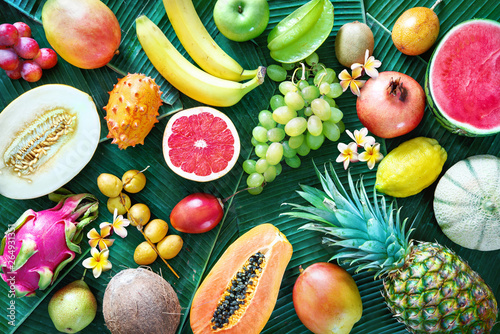 Assortment of tropical fruits on leaves of palm trees photo