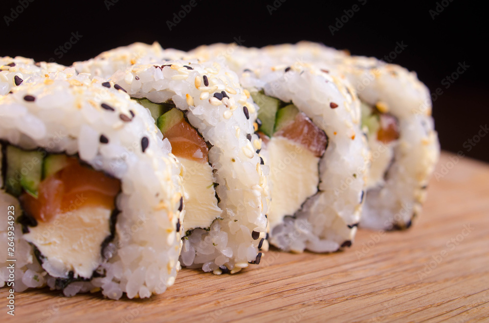 Sushi rolls with salmon and cheese. Japanese traditional cuisine. Rice with seafood. Menu maki rolls on a black background Sushi rolls with salmon and cheese. Japanese traditional cuisine. Rice with seafood. Menu maki rolls on a black background