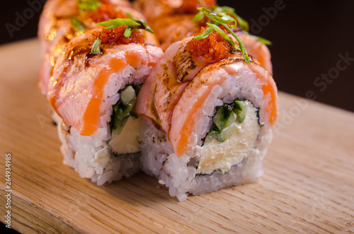 Beautiful sushi rolls with tuna on a wooden plank. Japanese sushi with fish in the Ukrainian seafood restaurant. Menu rolls on a black background
