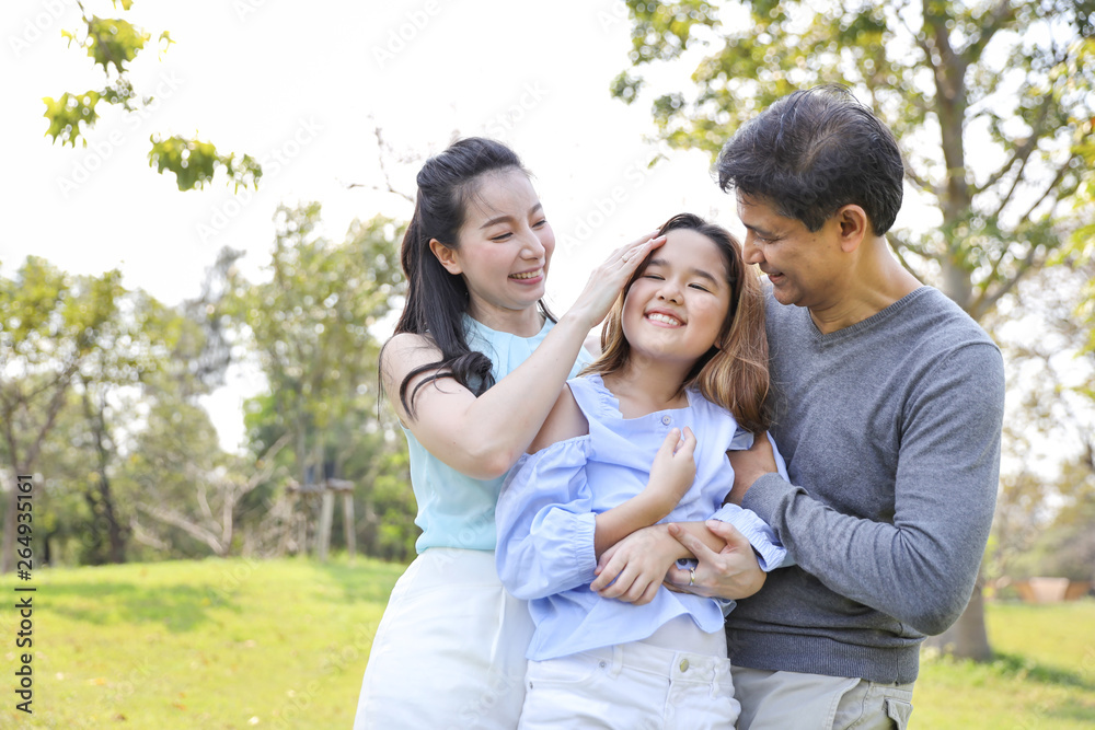 image of happy family, daughter putting her hands on parents cheek with smiling during summer time in the park image of happy family, daughter putting her hands on parents cheek with smiling during summer time in the park