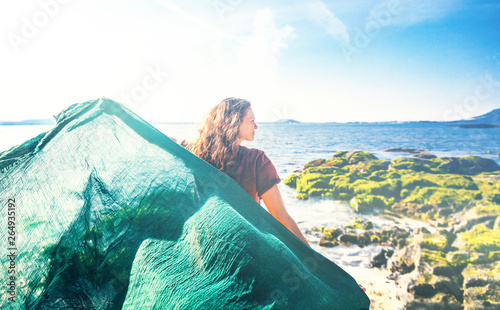 Beautiful happy young woman with green scarf on the seashore on a sunny spring day