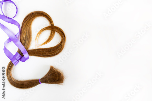 long blond hair donation put like heart with lavender ribbon as symbol of fight against cancer on white background. Top view. Natural material for making wig for patients. Horizontal isolated. Concept