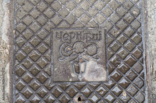 Close up of hatch (luke) in Chernivtsi, Ukraine. Metal rusty manhole cover in Bukovina, Eastern Europe. Grunge and texture concept. Translation: 