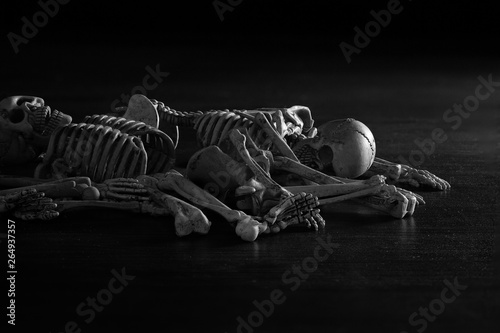 Fotografie Pile of human bones on dark brown wooden and adjustment color black and white for background