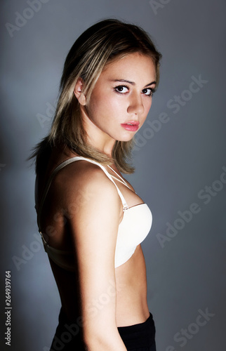 Young woman in bra standing shamed on grey background. Young affair concept.