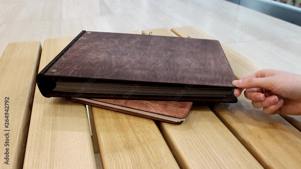 The girl opens and closes the album with empty pages. Family album, closeup of a hand and album. Wooden album on the rings. A book with a wooden cover. The girl opens and closes the album with empty pages. Family album, closeup of a hand and album. Wooden album on the rings. A book with a wooden cover.
