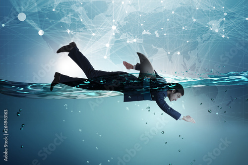 Businessman with shark fin swimming in water