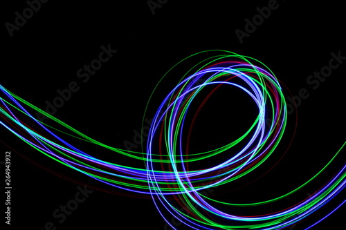 Long exposure, light painting photography. Vibrant colorful streaks of neon color against a black background.