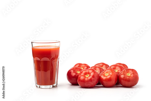 Tomato juice in a glass, with tomatoes on a white background