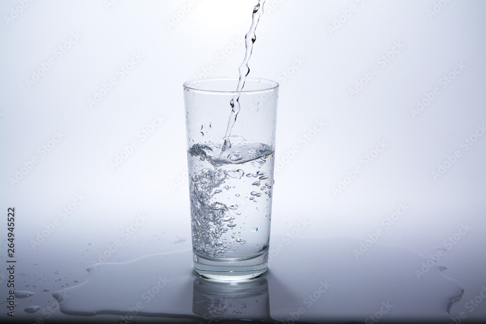 Pour clean drinking water into the glass on the table. Close-up. Pour clean drinking water into the glass on the table. Close-up.