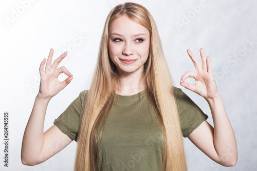 Young beautiful smiling woman shows ok sign. Body language concept.