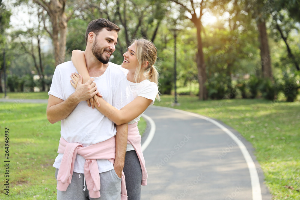 young caucasian couple in sport suit who in love hugging with smile and eyes contract together in the park during summer season young caucasian couple in sport suit who in love hugging with smile and eyes contract together in the park during summer season