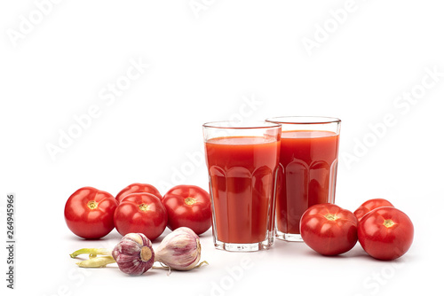 Tomato juice in a glass, with tomatoes, and garlic on a white background