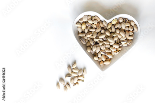 Nuts arranged in heart  on background. Healthy Food image close up pistachios on the cup plate. Love Texture on white grey table top view mock up