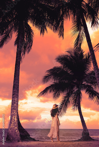 A beautiful  brunette  woman walking along the beach with an amazing sea sunset  in the background.-Image.