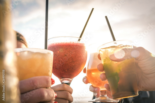 Greetings to best friends, group of friends enjoying evening drinks at the beach at sunset. Concept of vacation, carefree, end-of-day relaxation, celebration and well-being.