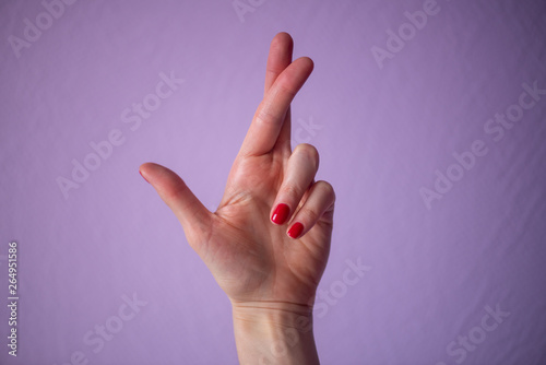 hand with thumb and middle finger up, isolated on purple background