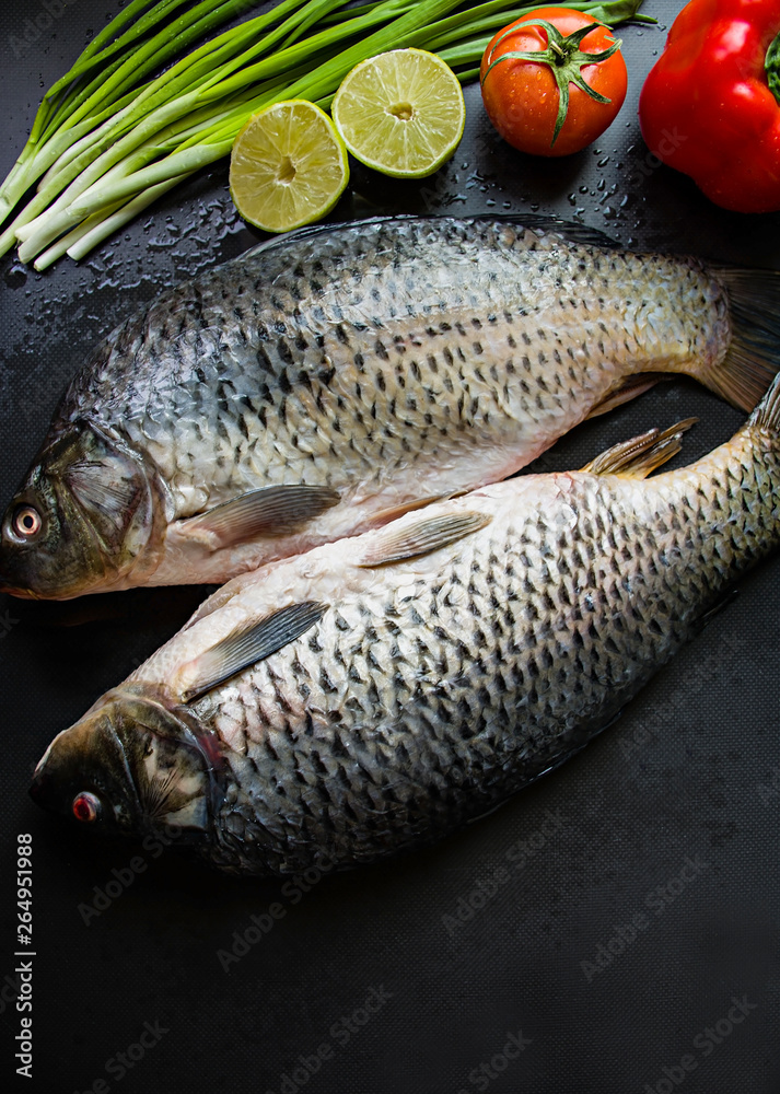 Fresh carp on a dark background with greens and vegetables. Fresh carp on a dark background with greens and vegetables.