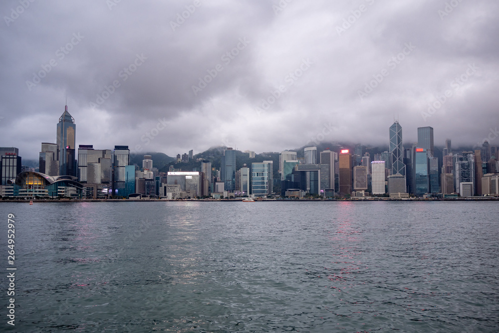 Fototapeta premium Beautiful panorama view of business district of hong kong city and river on overcast and clouds sky background
