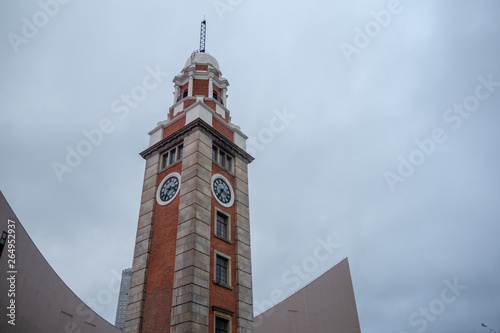 Low angle of clock tower in commercial district on overcast sky background with copy space