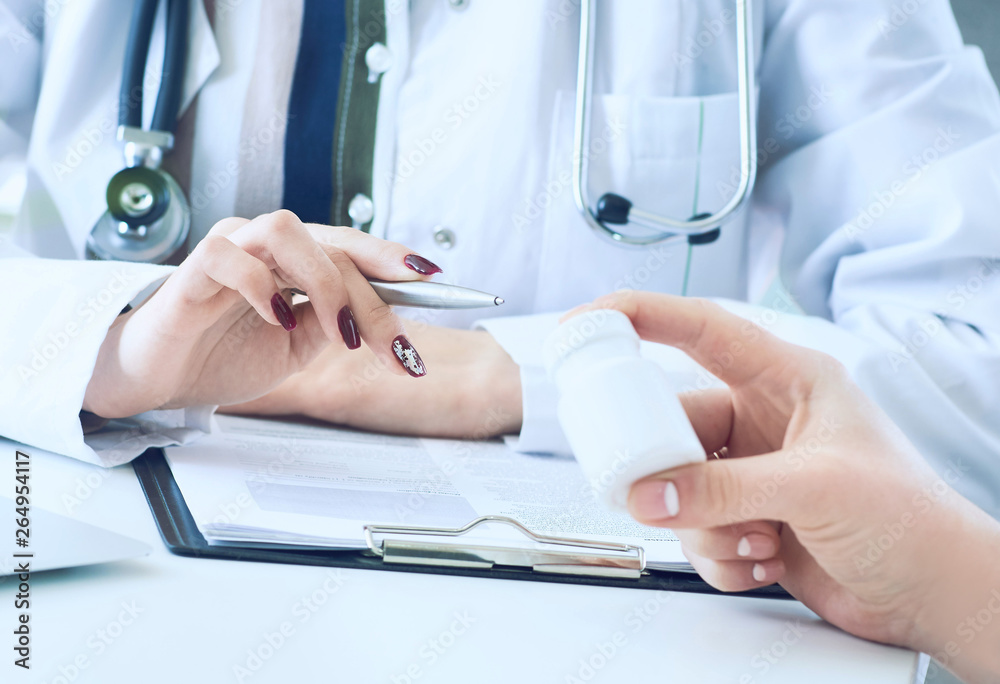 Female doctor hands gives jar of pills to patient hand closeup.