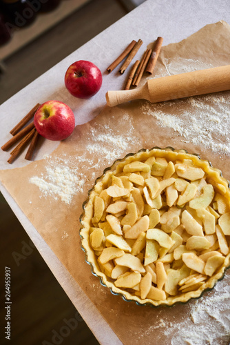 Apple pie tart homemade American traditional dessert pastry baked food preparation recipe with ingredients flat lay on table with parchment paper and flour, top view