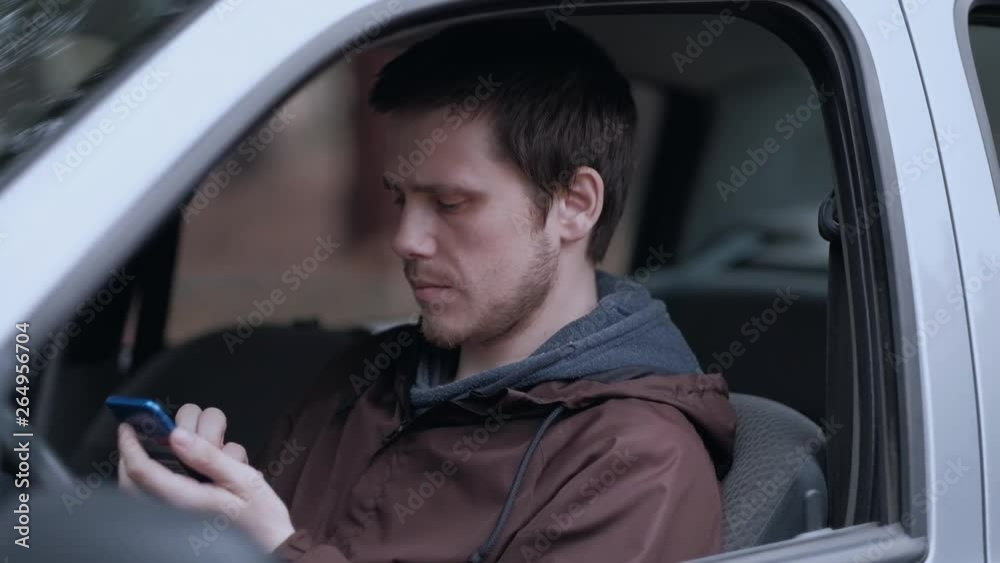 Close up shoot. Young man driver use smartphone, sitting in the car. Slowmotion. Close up shoot. Young man driver use smartphone, sitting in the car. Slowmotion.