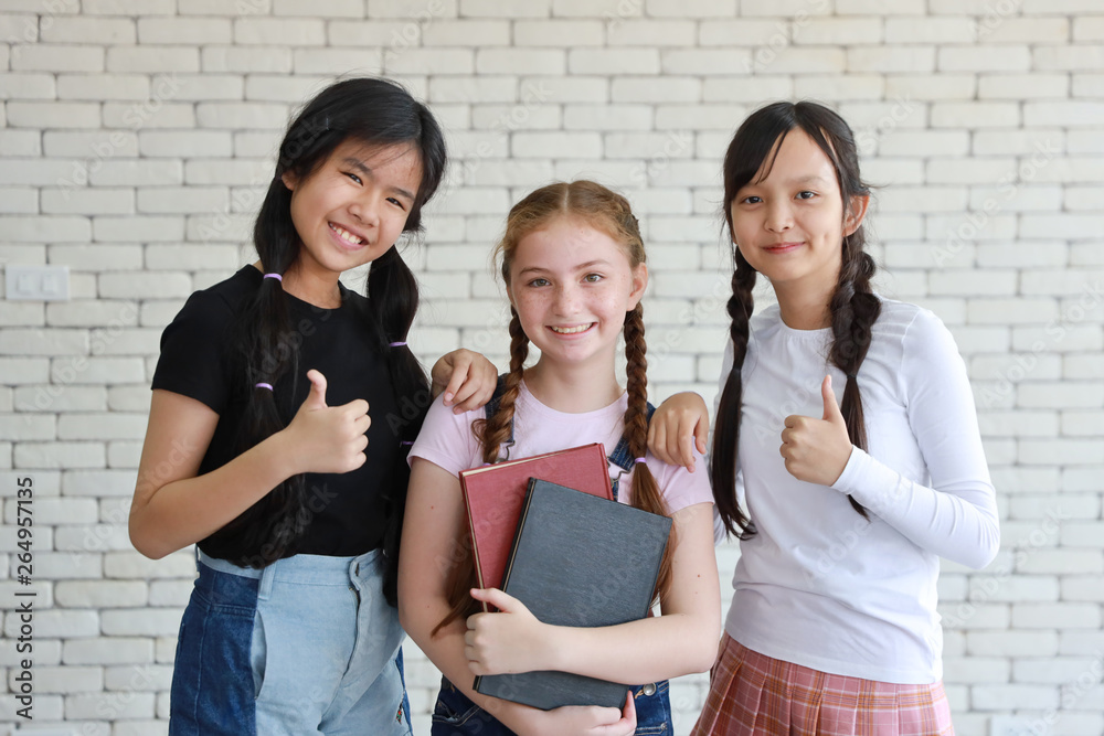 group of school girls holding books and showing thumb up group of school girls holding books and showing thumb up