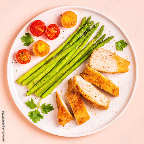Roasted chicken breast with asparagus and tomatoes.