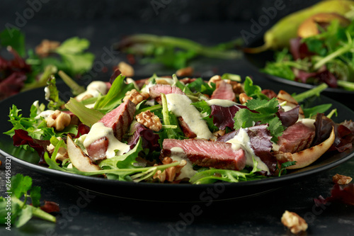 Grilled Beef Steak salad with pears, walnuts and greens vegetables and blue cheese sauce. healthy food.