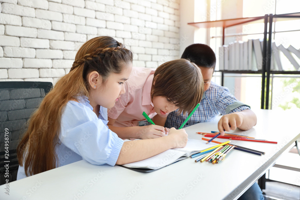 three school kids drawing in class (education concept) three school kids drawing in class (education concept)