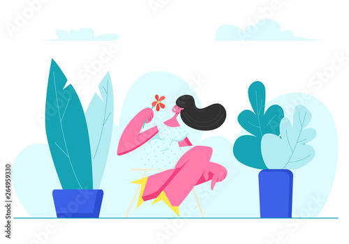Young Adorable Woman with Flower in Hands Sit on Stool Outdoors among Green Pants